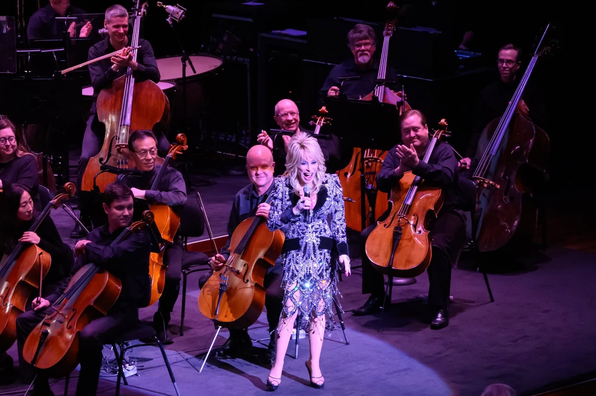 Dolly Parton speaking to the audience from among the cellists