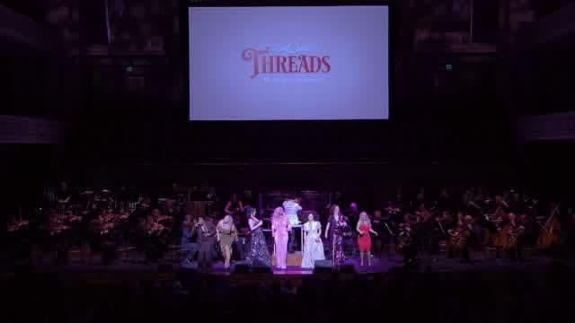The orchestra and singers on the Schermerhorn stage beneath the Threads title screen